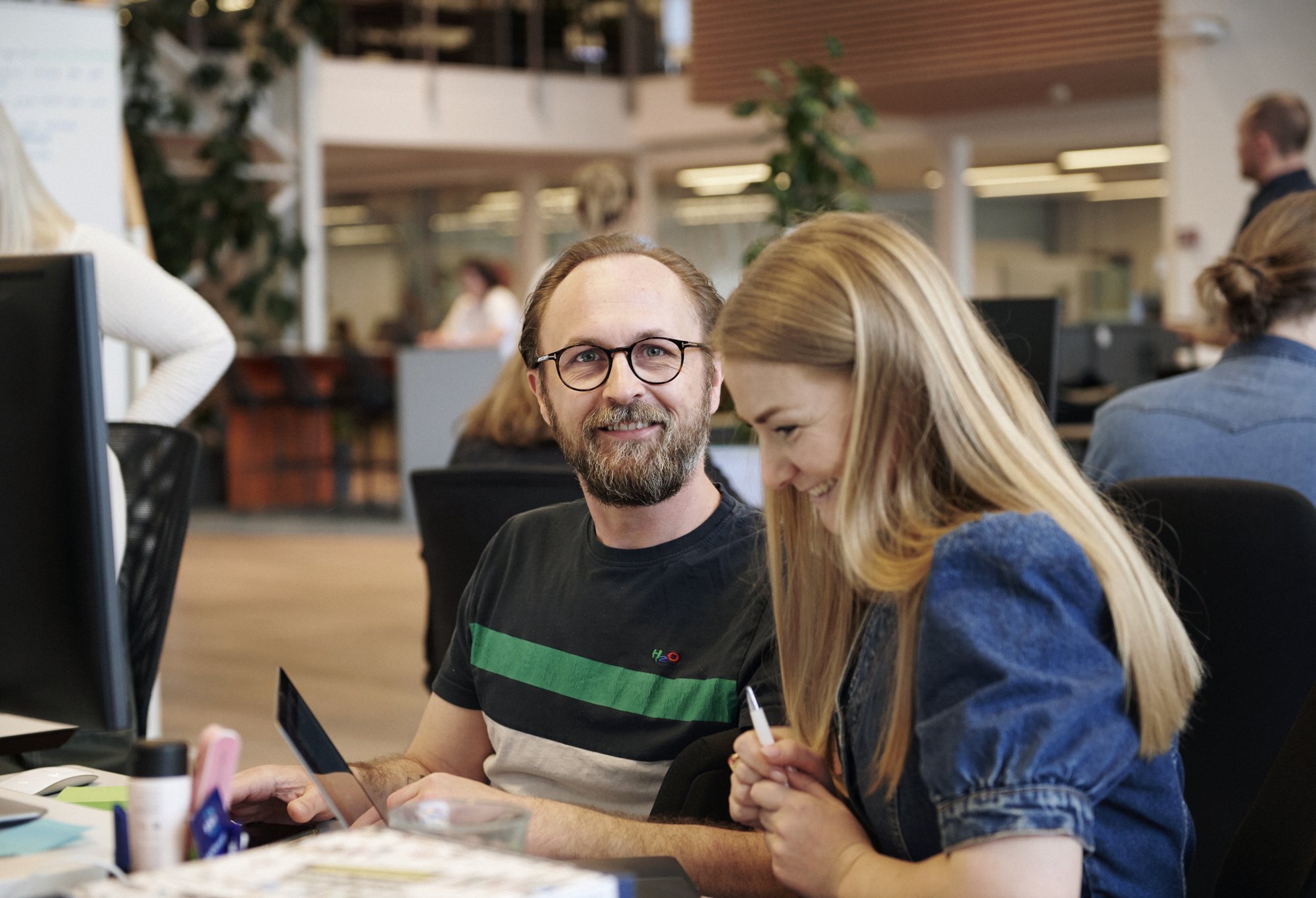 Twee collega's kijken lachend samen naar een scherm